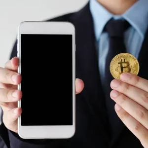 Hand holding bitcoin and smartphone