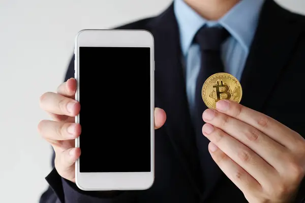 Hand holding bitcoin and smartphone